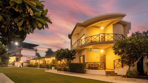 A hotel with a modern design, featuring a curved facade and a balcony. - Treebo Tiger Pug Mark Resort with Pool (Kaladhungi)