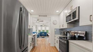 A modern kitchen with stainless steel appliances, white cabinetry, and a wooden floor. - Sail Away - Pet Friendly! (Jekyll Island)