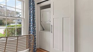 A laundry room with a large window, a washing machine, and a door with a black handle. - Sail Away - Pet Friendly! (Jekyll Island)