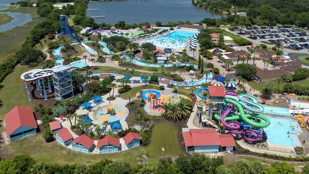 An aerial view of a water park with multiple pools, slides, and a large body of water in the background. - Sail Away - Pet Friendly! (Jekyll Island)