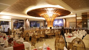 Ein Restaurant mit runden Tischen, Holzstühlen und einer großen Kronleuchter.