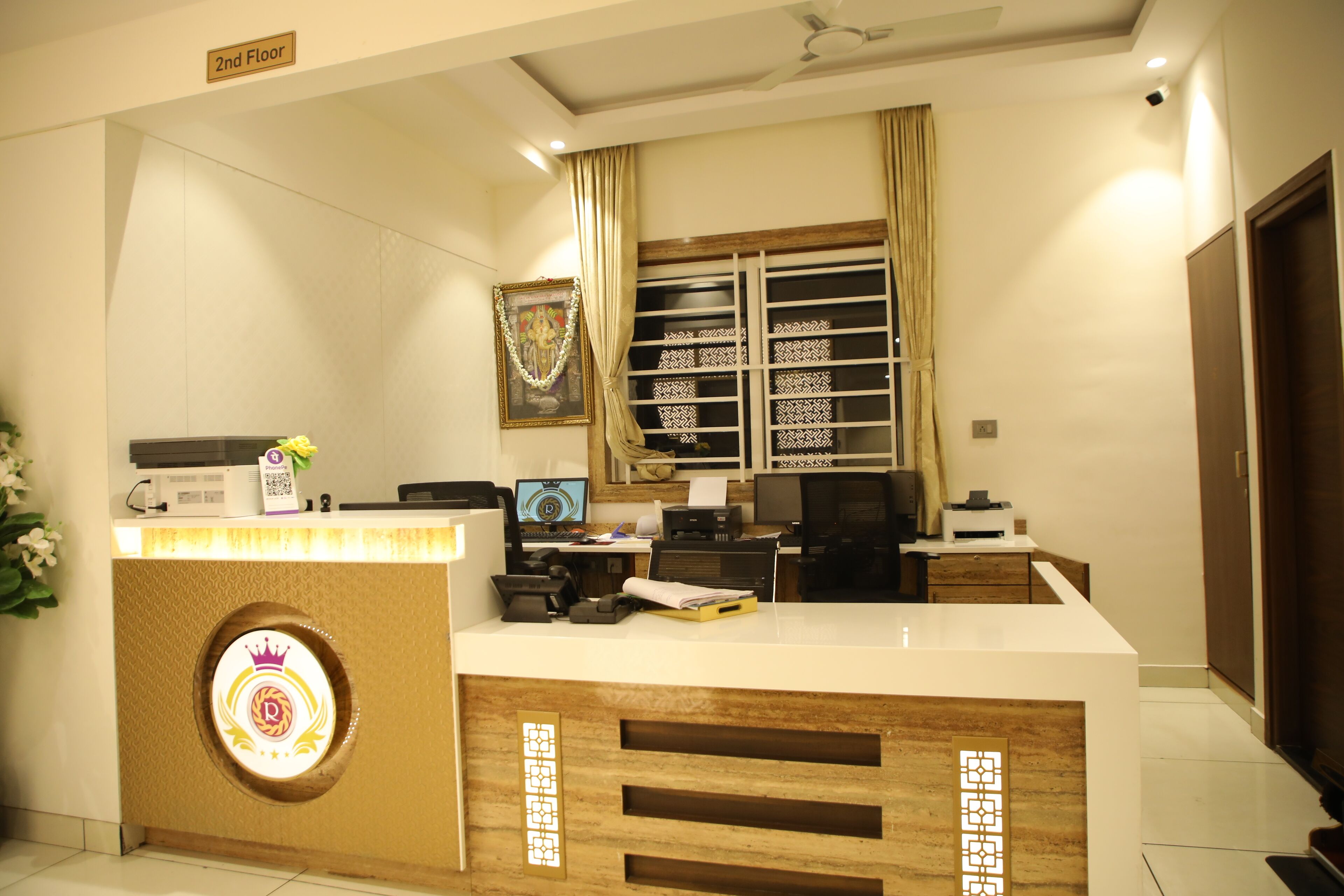 A reception desk with a crown logo, a computer, and a framed picture on the wall.