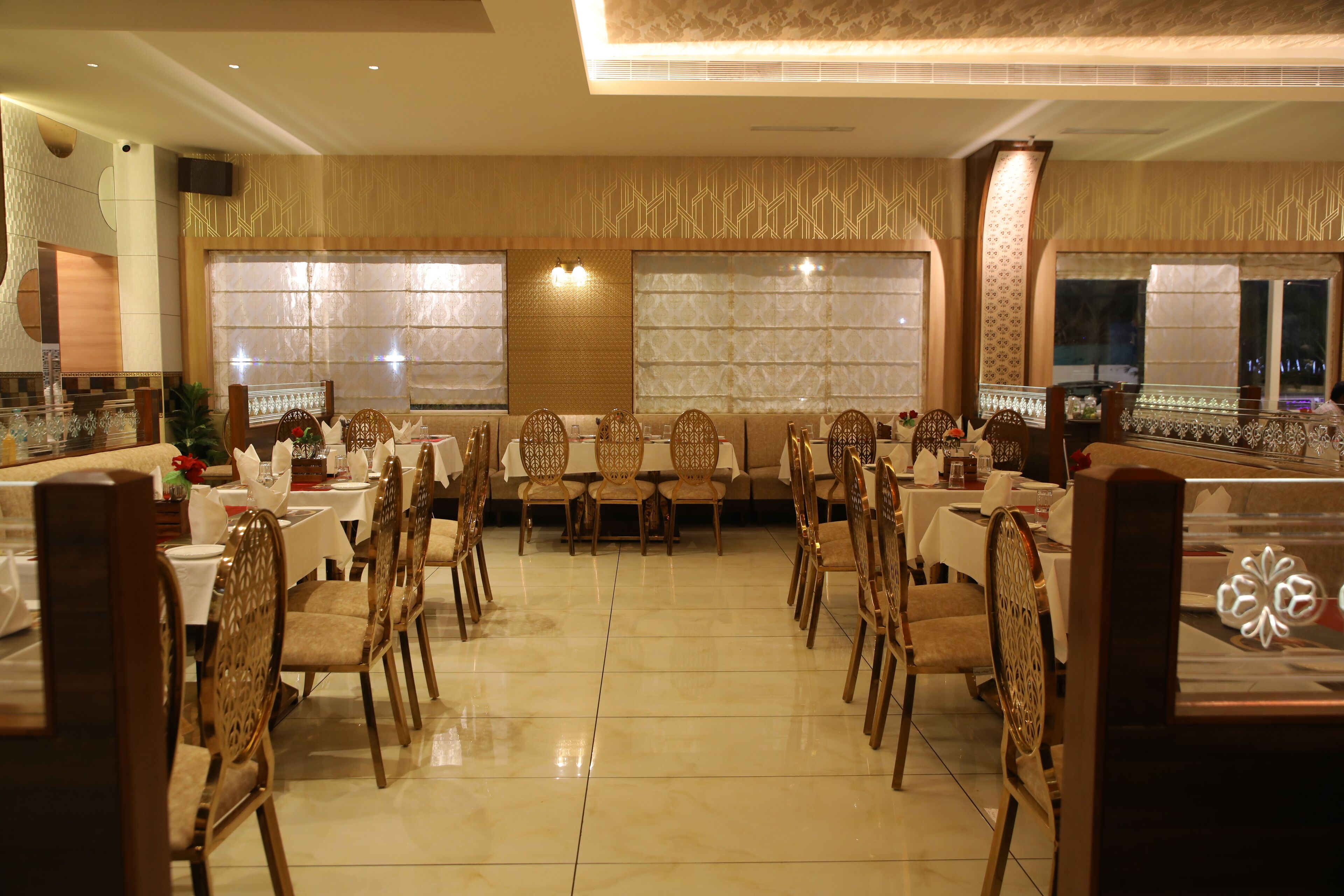 Un restaurante con un comedor central que presenta una larga mesa con sillas, rodeada de mesas y cabinas más pequeñas.