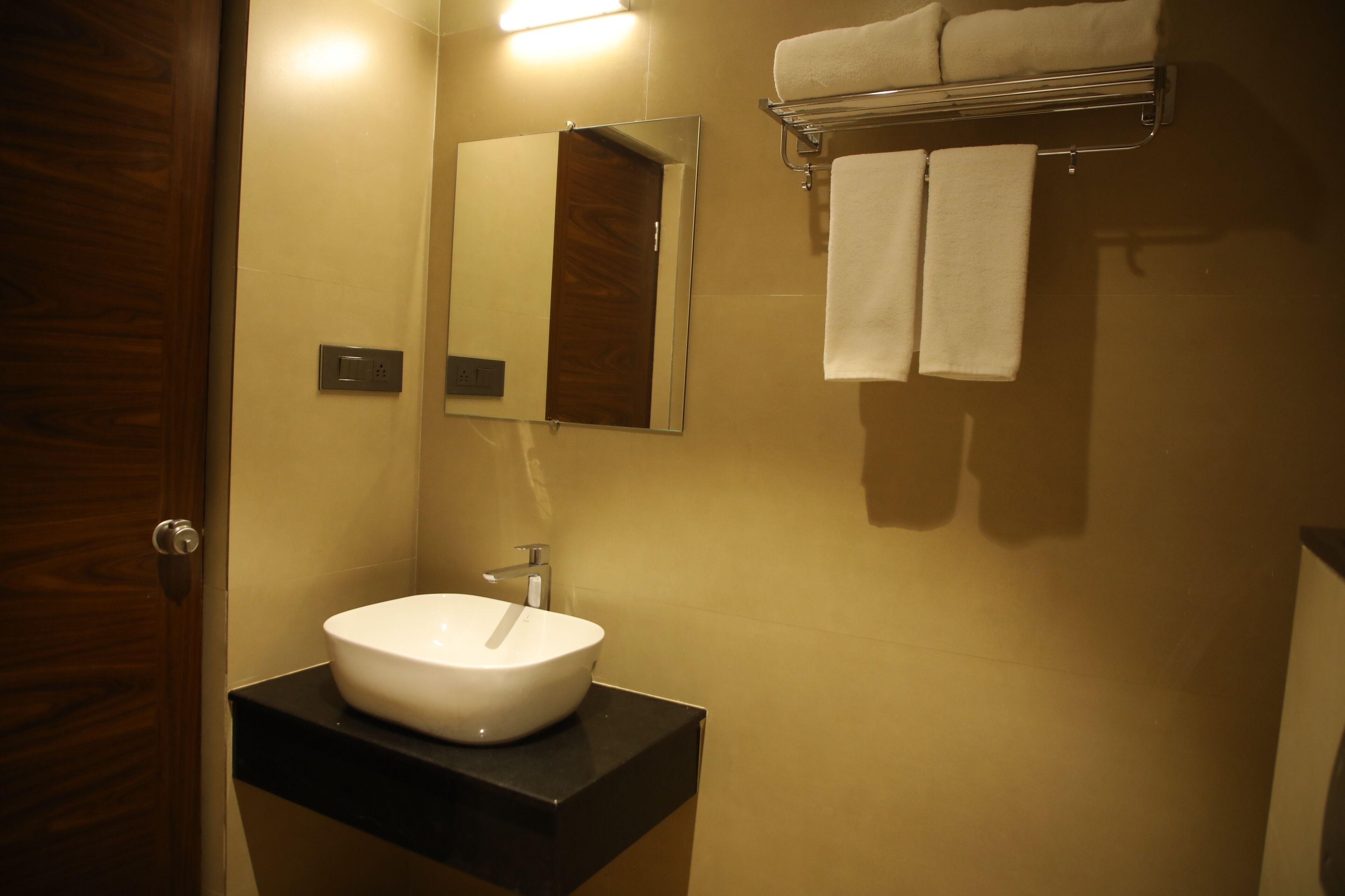 A bathroom with a white sink, a mirror, and two towels hanging on a rack.