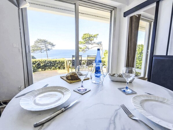 A dining table with plates, cutlery, and glasses, set against a backdrop of a scenic view through large windows.