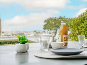 A table set with white dishes, a bottle of juice, and a small potted plant.