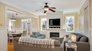 A living room with a sofa, TV, fireplace, and ceiling fan.