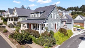 A two-story residential house with a porch, a red door, and a well-maintained garden.