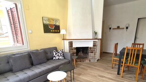Un salon comprenant un canapé, une petite table ronde, une cheminée et un coin repas avec des chaises.