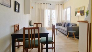 Un coin repas avec une table et des chaises, un canapé et un balcon agrémenté de rideaux.