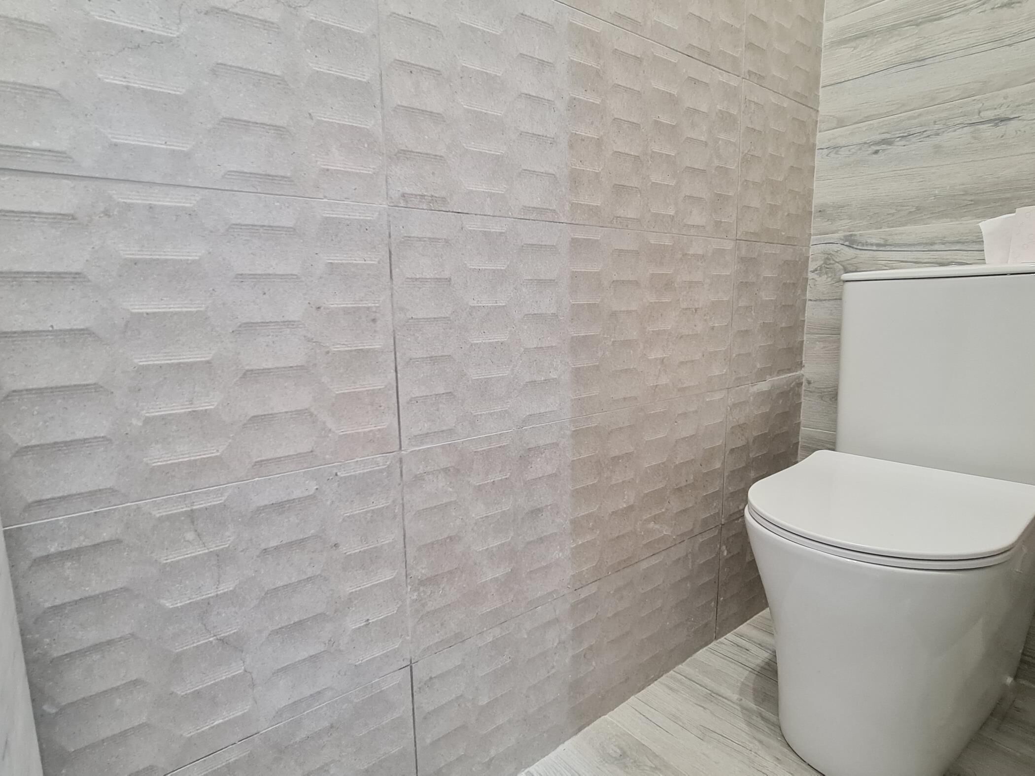 A bathroom with a textured wall and a white toilet.
