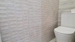 Un baño con pared texturizada y un inodoro blanco.