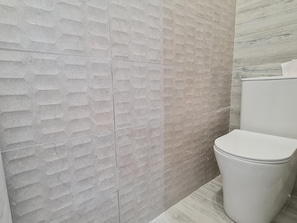 A bathroom with a textured wall and a white toilet.