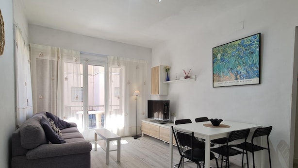 Una sala de estar moderna con sofá, mesa de comedor, sillas y televisor.