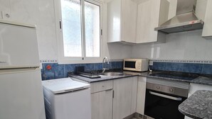 Una cocina equipada con refrigerador, microondas, horno y pileta.