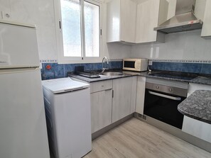 A kitchen with a refrigerator, microwave, oven, and sink.