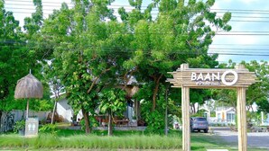 A sign for BAAN hotel with a thatched roof structure and lush greenery in the background. - Baan O Resort (Rayong)