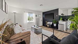 Uma sala de estar moderna com sofá, mesa de centro e vista para a cozinha.