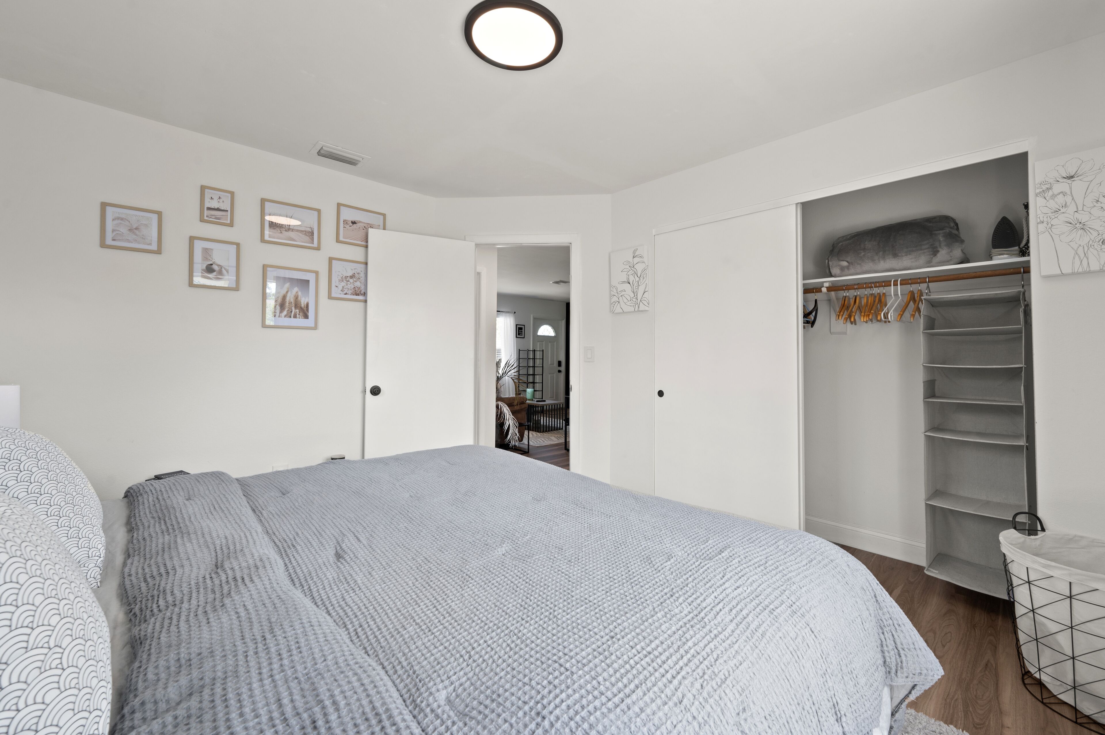 A bedroom with a large bed, a walk-in closet, and a hallway leading to another room.