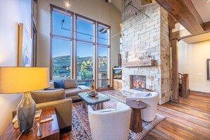 A spacious living room with large windows, a stone fireplace, and a cozy seating area.