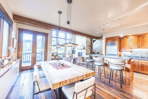 Een ruime keuken met houten kastjes, een groot eiland met barstoelen en een eethoek met een houten tafel en stoelen.