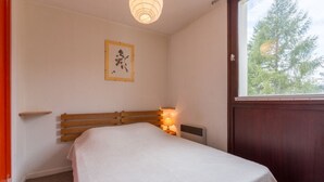 A single bed with a wooden headboard, a bedside lamp, and a framed picture on the wall. - Cosy apt 4/6 ppl with balcony, near the ski runs (Les Deux Alpes)