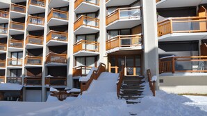 A multi-story hotel with wooden balconies and a snow-covered entrance. - Cosy apt 4/6 ppl with balcony, near the ski runs (Les Deux Alpes)