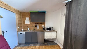 A compact kitchen with a dishwasher, microwave, and wooden cabinets. - Les 2 Alpes studio 2 ppl with ski station view (Les Deux Alpes)