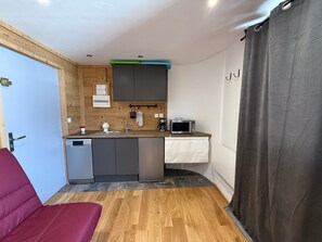 Eine kleine Küche mit Geschirrspüler, Mikrowelle und Holzschränken.