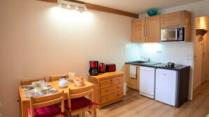 A compact kitchen with wooden cabinets, a microwave, a toaster, and a coffee maker. - Andromede - 35 - Studio coeur station - 4 pers (Les Deux Alpes)