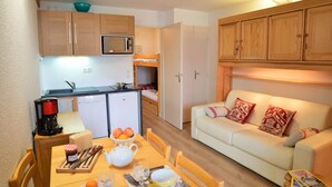 A compact living space with a kitchenette, a dining area, and a sofa. - Andromede - 35 - Studio coeur station - 4 pers (Les Deux Alpes)
