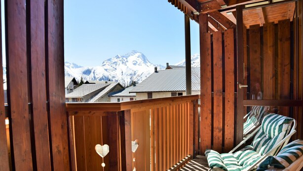 A wooden balcony with a view of snow-capped mountains, a wooden pergola, and striped lounge chairs. - Andromede - 35 - Studio coeur station - 4 pers (Les Deux Alpes)