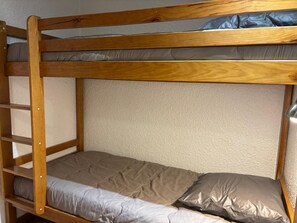 Una cama litera con estructura de madera y un colchón con cubierta acolchada.