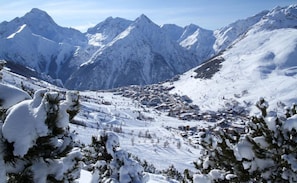 Un paysage montagneux enneigé, avec un petit village niché au fond de la vallée.