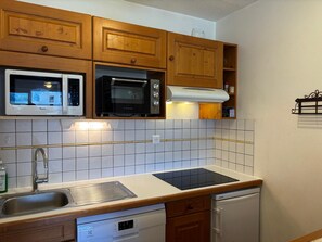 Une cuisine avec des meubles de rangement en bois, un four à micro-ondes, une cuisinière et un lave-vaisselle.