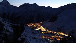 A snow-covered mountainous landscape with a lit valley below.