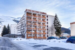 Ein mehrstöckiges Hotel mit Balkonen, einem Parkplatz und verschneiter Umgebung.