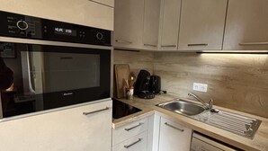 A modern kitchen with a built-in oven, a coffee machine, a sink, and a dishwasher. - Studio 4 ppl near the ski runs (Les Deux Alpes)