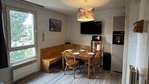 A compact living space with a dining area, a sofa, a TV, and a kitchenette. - Studio 4 ppl near the ski runs (Les Deux Alpes)