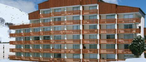 A multi-story hotel with balconies, set against a snowy landscape.