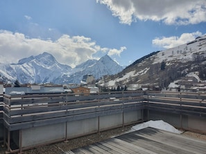 Terraço no telhado com vista para montanhas cobertas de neve e céu claro.