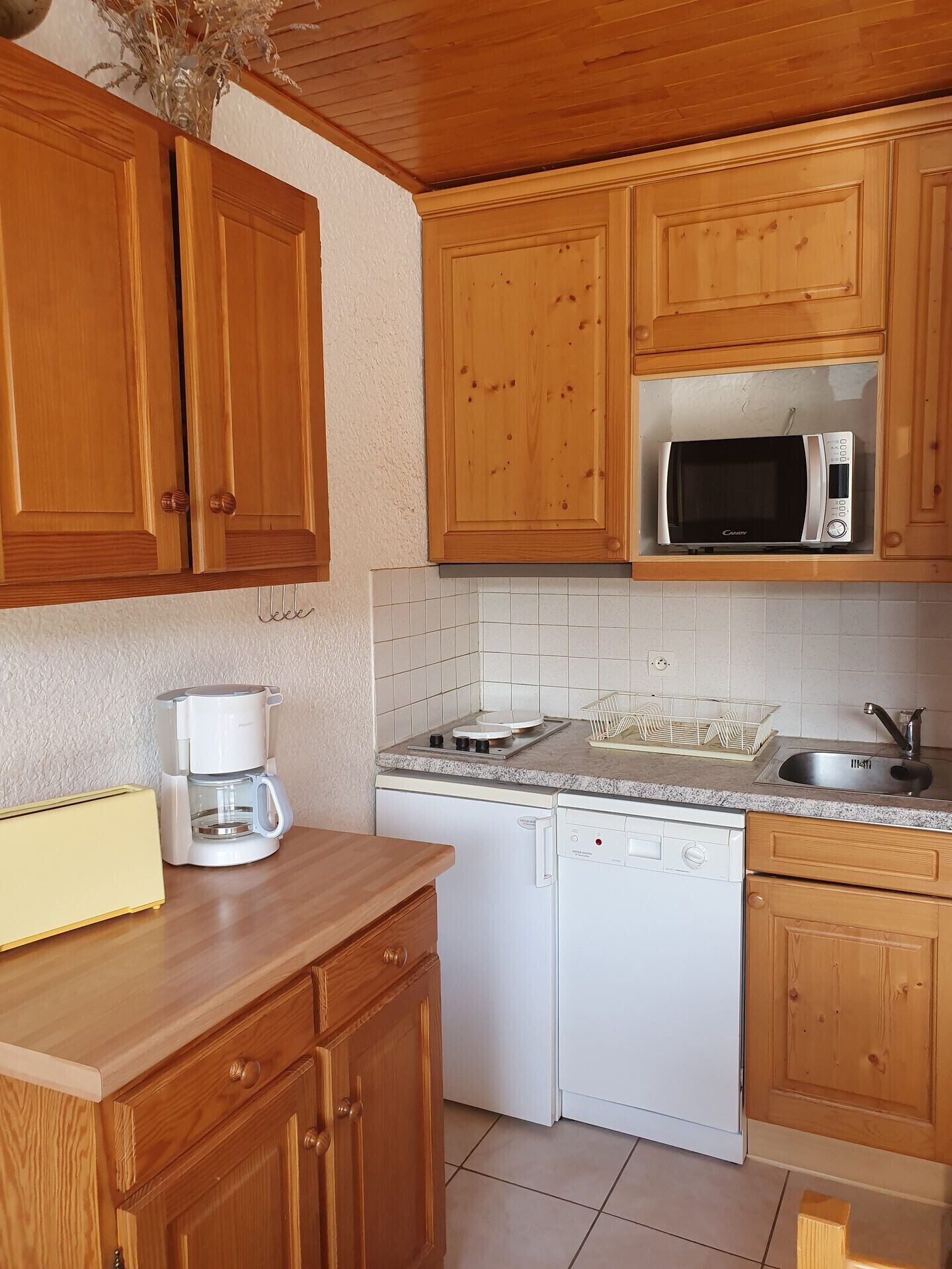 A kitchen with wooden cabinets, a microwave, a coffee maker, a dishwasher, and a sink.