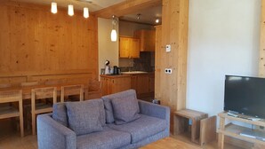 Un intérieur en bois avec un canapé, une table à manger et un meuble pour la télévision.