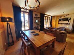 Un salon chaleureux avec une table à manger en bois, deux canapés, un lampadaire et un ventilateur de plafond.