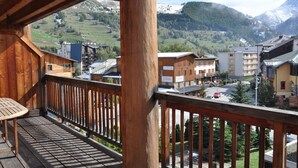 A wooden balcony with a view of a mountainous landscape and buildings. - Wonderful apt 8 ppl with mountain view (Les Deux Alpes)
