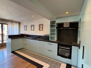 A modern kitchen with a black countertop, white cabinets, and a patterned floor. - Spacious apt 10 pers, terrace, ski station (Les Deux Alpes)
