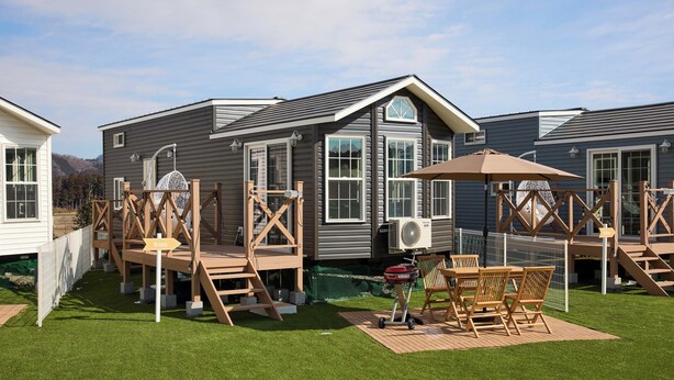 A residential area with houses, a wooden deck, and a grill.