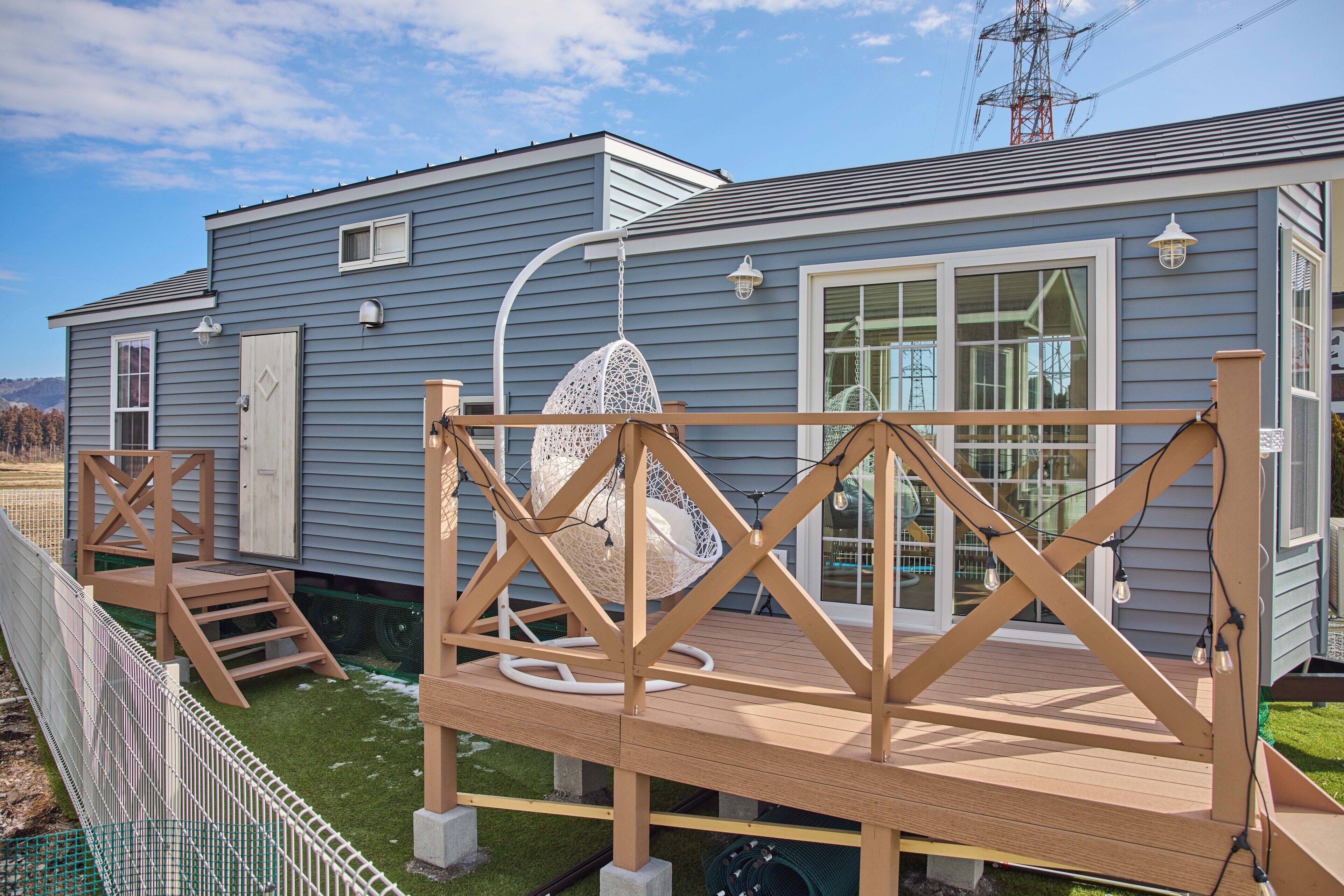 A residential building with a deck, a hanging chair, and a window with a view of the sky.