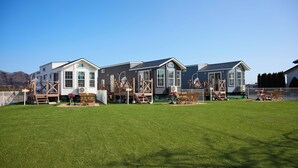 A row of modern houses with large windows, a well-maintained lawn, and a clear sky.