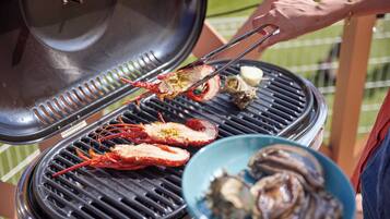 A grill with seafood, including lobsters and oysters, being cooked.